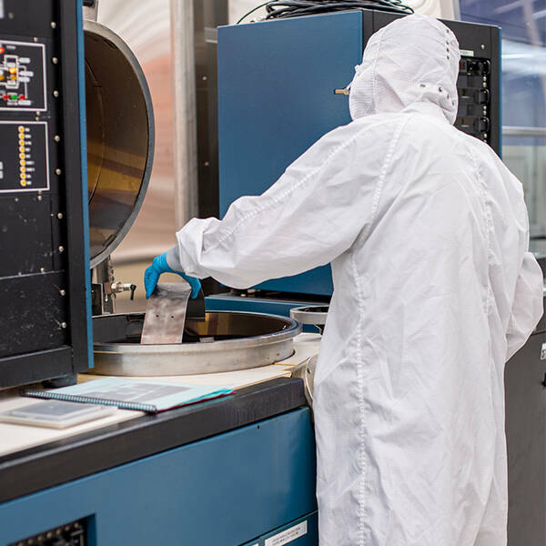 Individual in clean room suit works with the electron beam vacuum deposition system